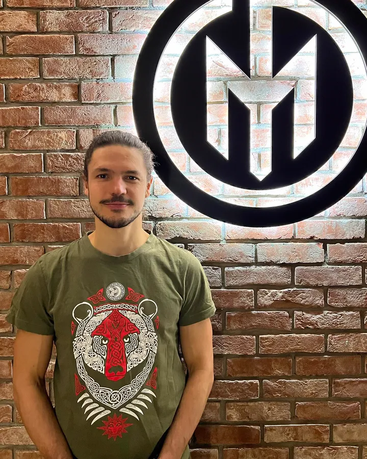 Martin u cihlové zdi s logem fitka
