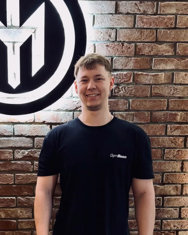 Vašek s úsměvem u cihlové zdi s logem fitka